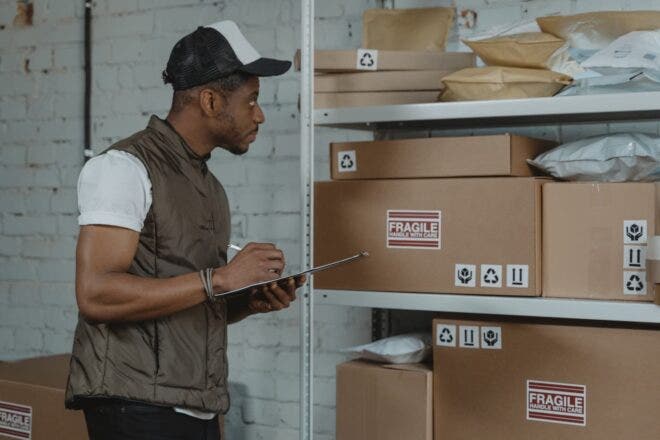 Man holding clipboard checking boxes on a shelves