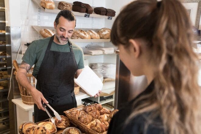 Bakery worker grabbing pecan roll for customer