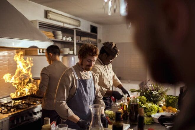 Three chefs preparing food in kitchen