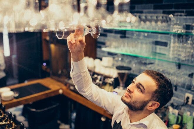 Bartender stocking glasses behind a bar