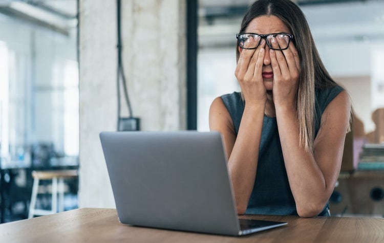 Woman rubbing eyes under glasses