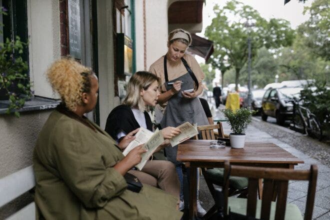 Waitress taking orders from two women holding menus