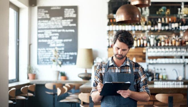 Restaurant owner writing on clipboard