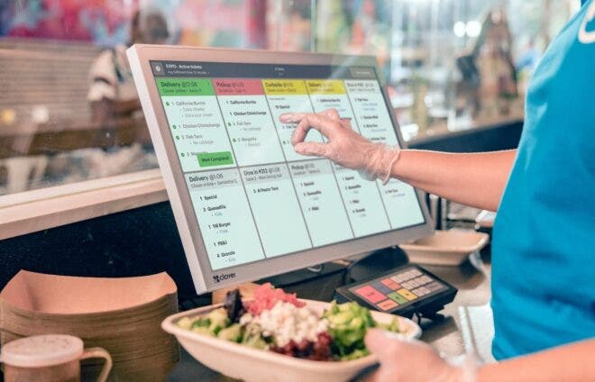 Restaurant worker tapping order on Clover KDS 24"