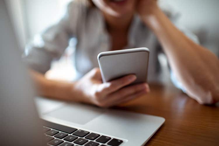 Person holding phone in front of laptop