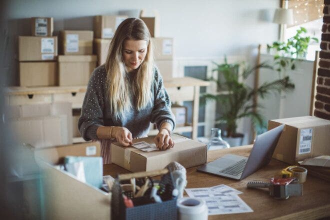 Woman applying shipping label to box
