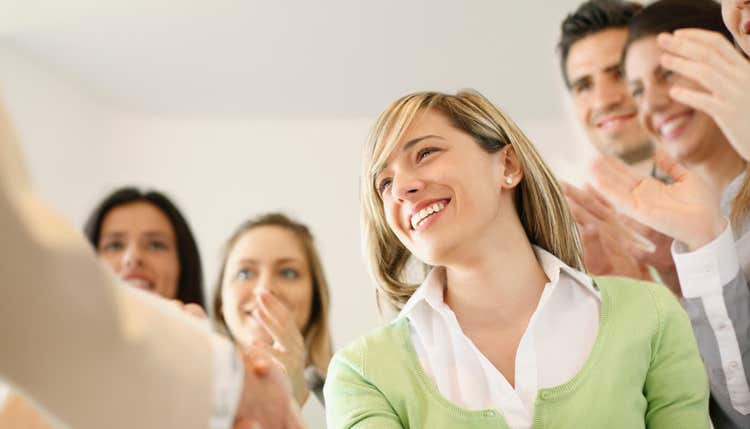 Woman shaking hands and people clapping