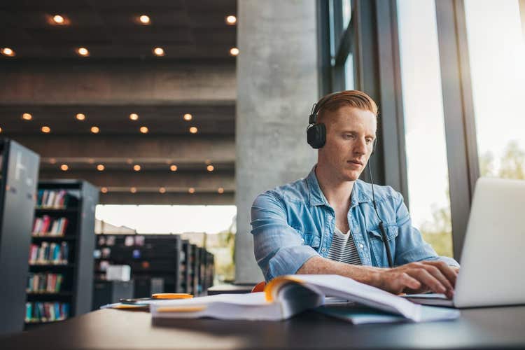 Young man in library working on laptop
