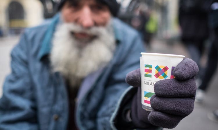Homeless man holding change cup