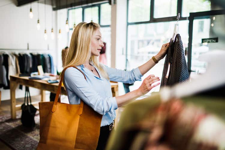 Woman holding up blouse at thrift shop