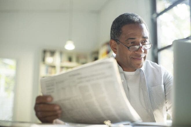 Man looking at computer screen holding papers