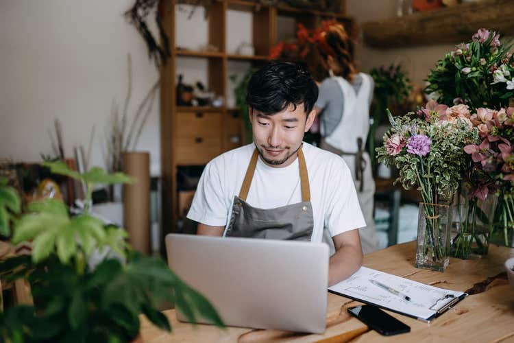Flower shop owner looking at laptop