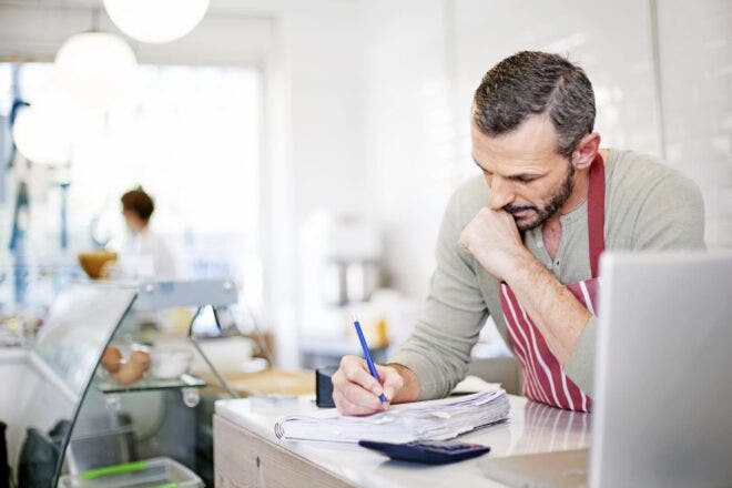 Cafe owner writing in notebook on counter