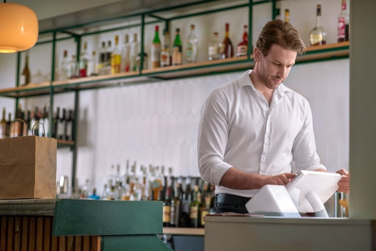 Man behind bar using clover pos station