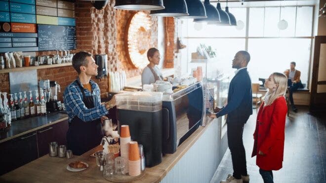 Two baristas behind counter at coffee shop