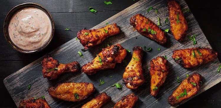 Wings and dipping sauce on a wooden platter from The Wing Suite