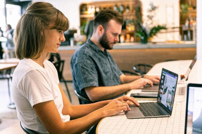Two people creating visual content on laptops