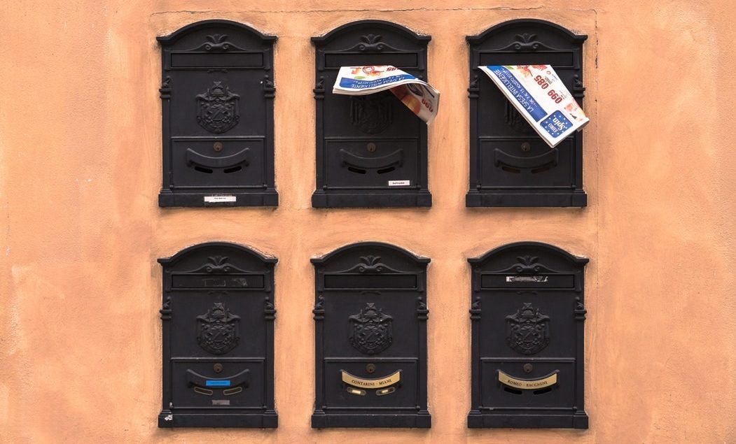 Six mailboxes with mail sticking out
