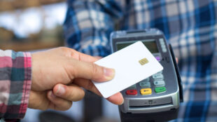 Man holding a POS device while another man taps his credit card onto the device.