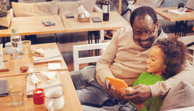 Man and child looking at tablet in restaurant