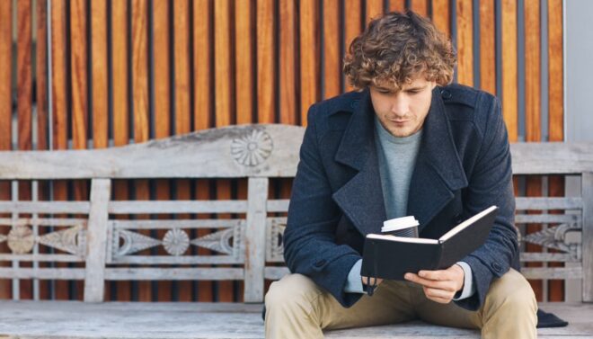 Man reading a book on a bench
