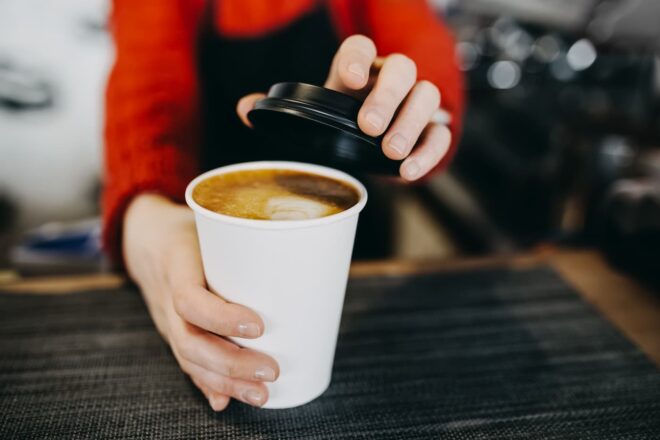 Barista putting lid on coffee cup