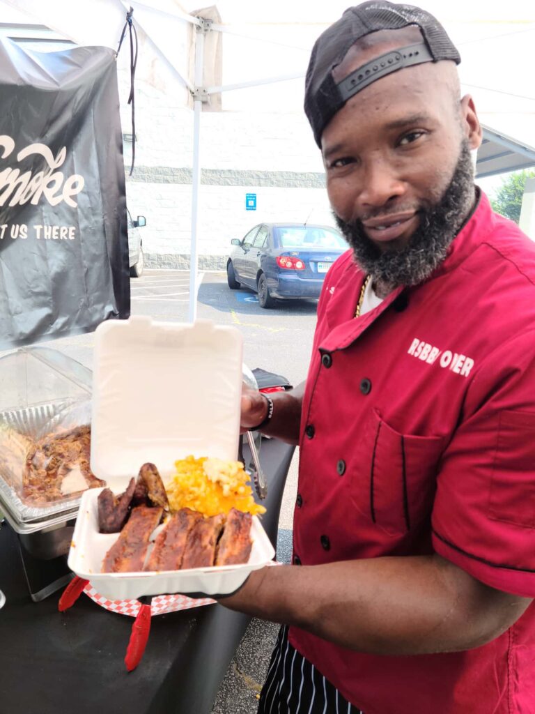 Dejuan Smith holding takeout box with ribs and mac n' cheese