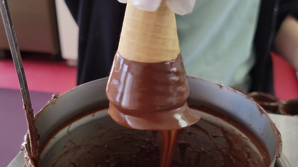 Dipping sugar cone into chocolate