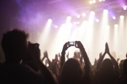 Concert goers with hands up taking mobile video