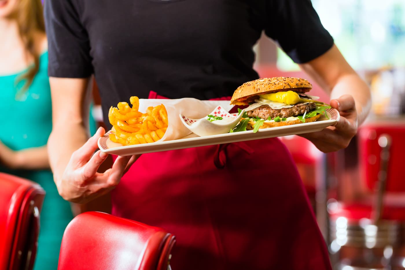 Waitress serving burger and fries in diner