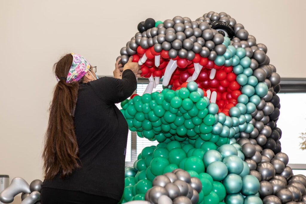 Owner of Rose City Balloons sculpting Godzilla out of balloons
