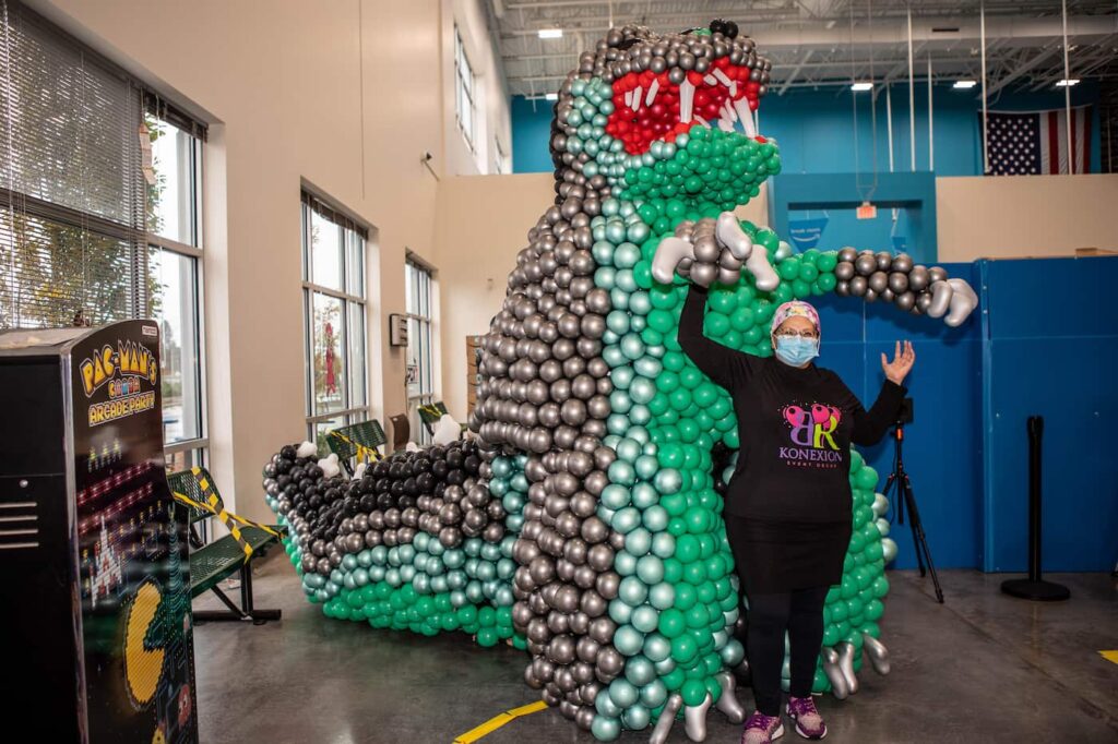 Rose City Balloons owner standing in front of Godzilla balloon sculpture
