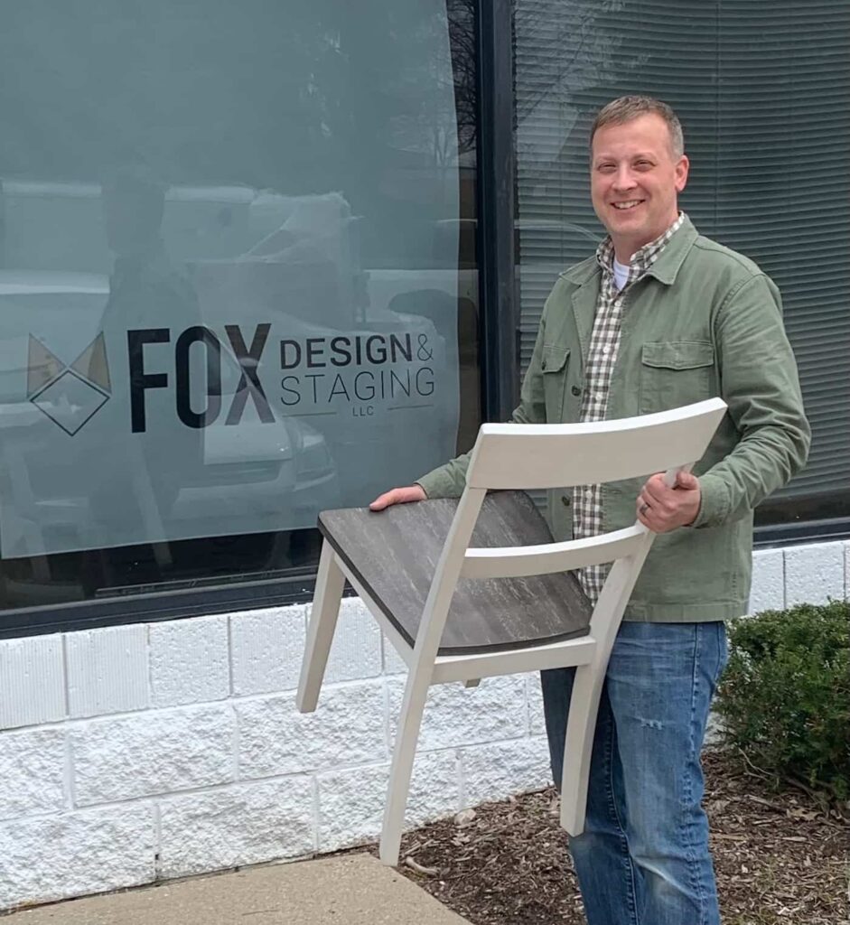 Andron Fox holding chair in front of his storefront