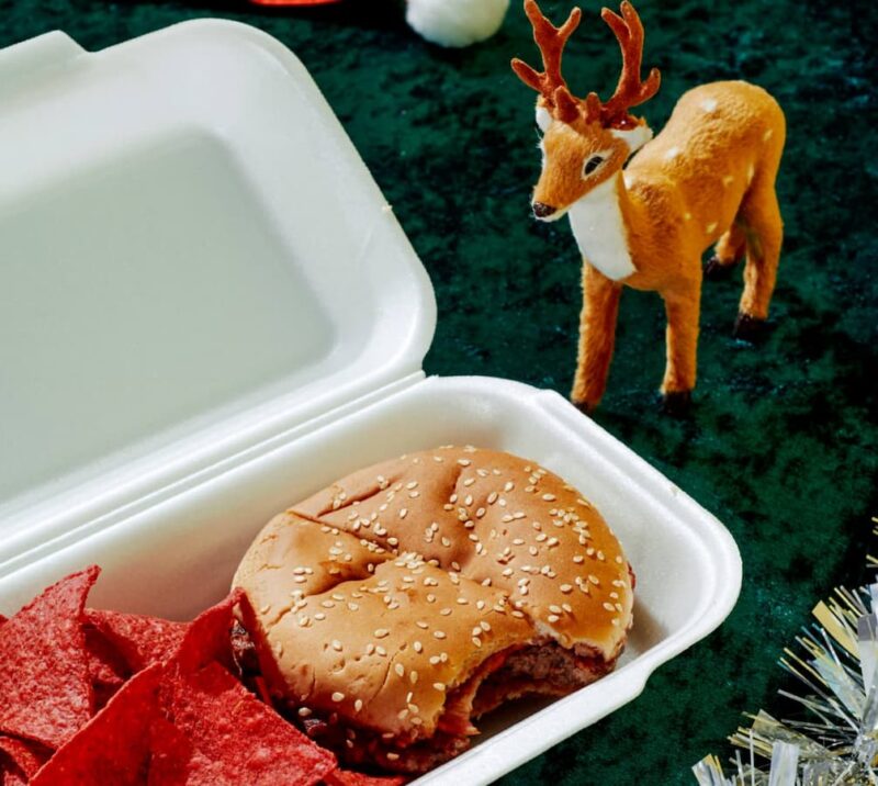 Tiny reindeer next to cheeseburger in takeout box