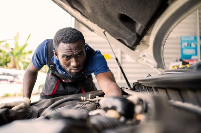 Auto mechanic looking under the hood of a car