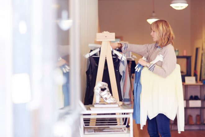 Boutique owner hanging up clothes on rack