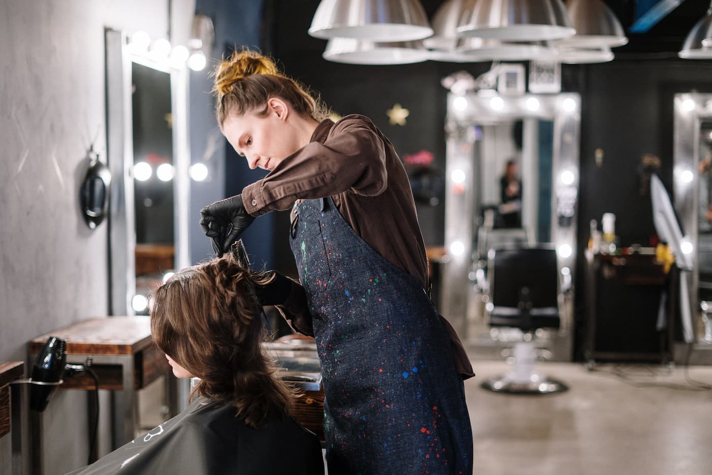 Stylist cutting woman's hair at salon