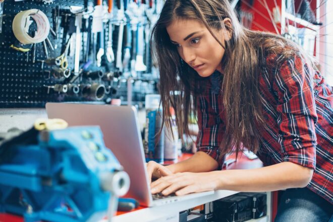 Woman working on laptop in repair shop