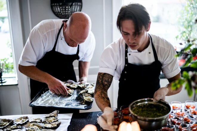 Two caterers plating oysters and appetizers