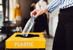 Person putting plastic bottle in recycling container