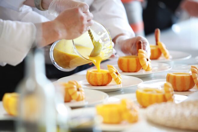 Chefs pouring soup into small pumpkin gourds