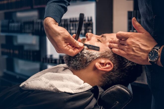Barber shaving customer with straight razor