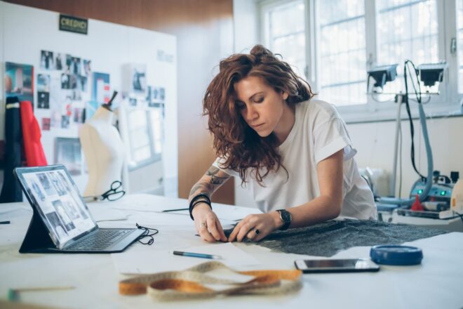 Young female fashion designer pinning fabric