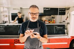 food truck owner standing with calculator