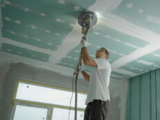 Painter sanding ceiling inside a home