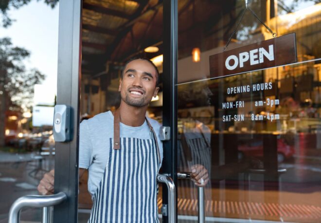employee holding restaurant door open for business