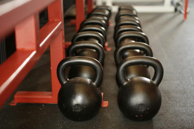 Row of kettlebells lined up against a workout bench in a gym