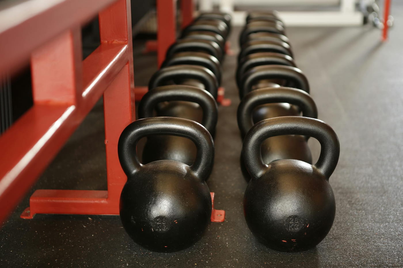 Row of kettlebells lined up against a workout bench in a gym