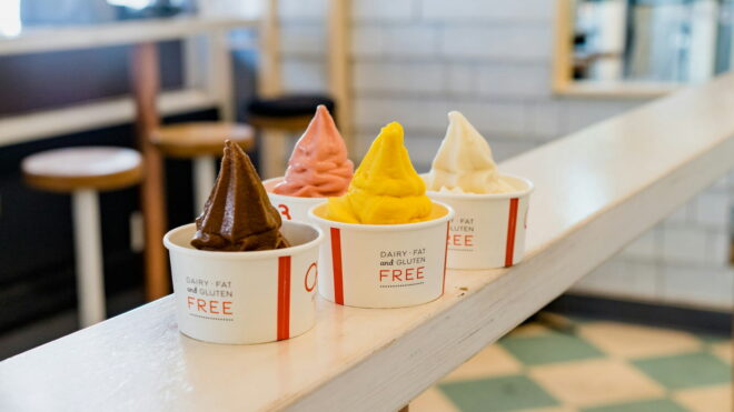 Four frozen yogurt cups with different flavored yogurt sitting on a yogurt shop countertop