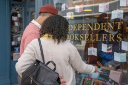 Man and woman standing outside an independent bookstore looking through the window at books